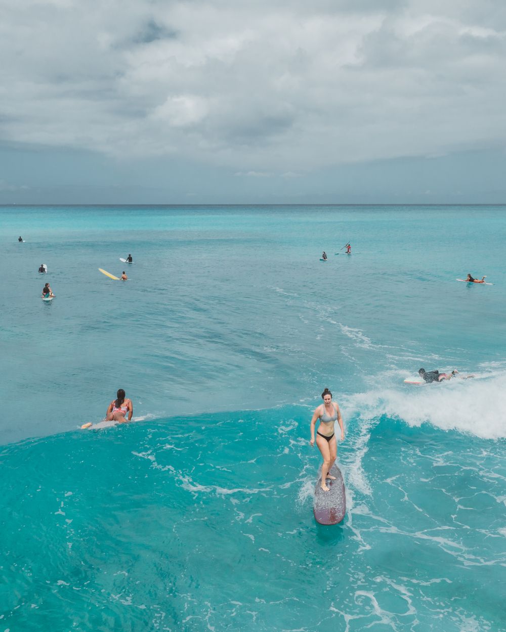 Surfers sharing a turquoise wave off Oahu, Hawaii